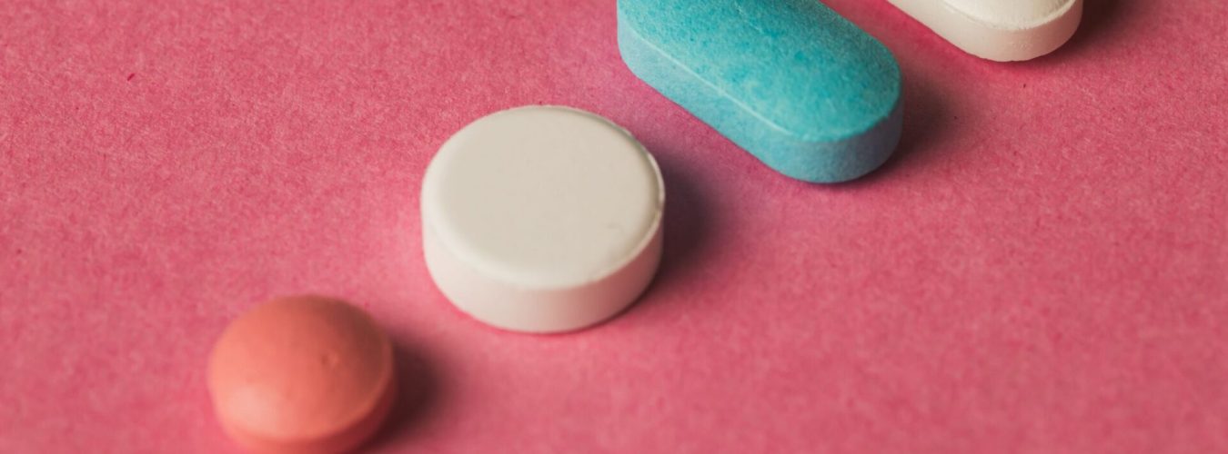 A closeup of pills arranged on a pink surface