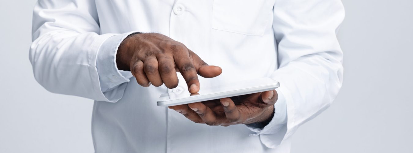 Cropped of african male doctor using digital tablet over white