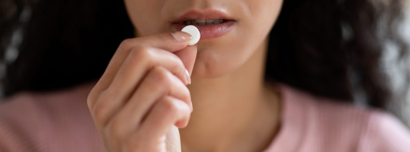 Unrecognizable Young Woman Taking White Round Pill At Home, Brunette Lady Suffering From Headache Or Eating Beauty Supplement, Close Up Shot, Cropped Image